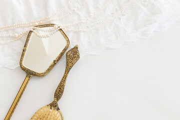 Background of white delicate lace fabric, pearls and vintage hand mirror