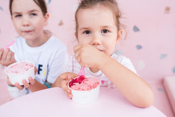 Summer food. Two adorable caucasian girls eating ice cream in cafe. Happy sisters are having sweets in gelateria. Childhood concept. Selective focus