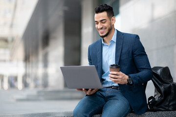 Positive project manager sitting next to business center with laptop