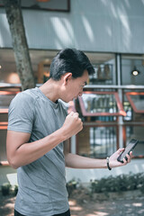 young man in hopeful , yeah and satisfy emotion when his look at mobile phone