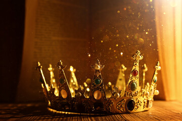 low key image of beautiful queen or king crown in front of old book. vintage filtered. fantasy...