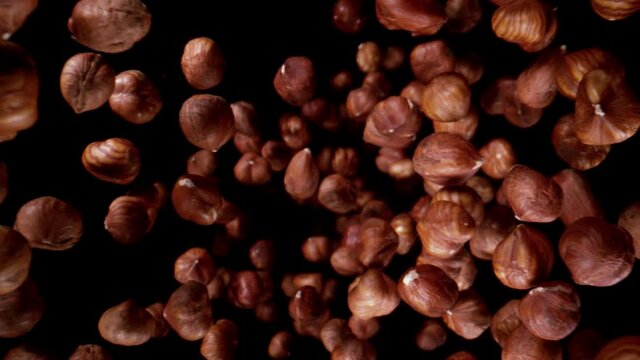 Super slow motion of falling hazelnuts, wide super macro shot. Isolated on black background. Speed ramp effect. Filmed on high speed cinema camera, 1000fps.