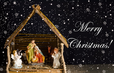 Christmas card with figures of Jesus, Virgin Mary and Joseph on a dark background with the inscription Merry Christmas.