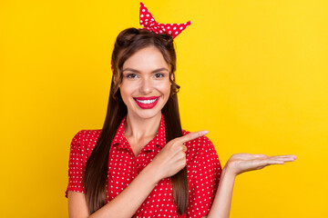 Photo portrait woman in red outfit showing finger blank space keeping on palm isolated vivid yellow color background