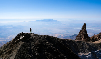 Hiker ascending top of volcanic mountain in daytime