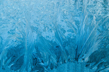 Frosty patterns on glass. Christmas background. Blue ice on winter window.