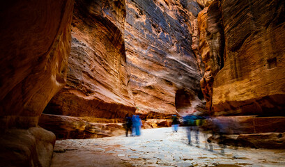 Group of people between sandstone rocks at narrow path in Petra, Jordan