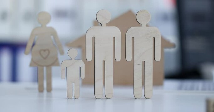 Wooden figurines of male married couple with child in background pregnant woman with house slow motion 4k movie