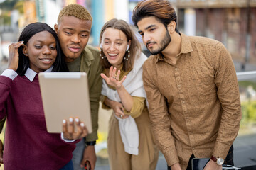 Multiracial students watching something on digital tablet outdoors. Concept of education. Remote...