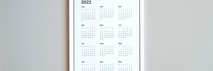 tablet computer with an open app of calendar for 2022 year on a gray background. concept business or to do list goals with technology using. top view, flat lay. banner