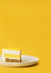 Delicious mango and passion fruit mousse cake slice with the layers and texture displayed on bright yellow background. Restaurant menu and confectionery concept. Close-up. Copy space.