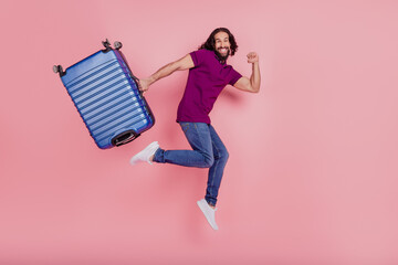 Full size profile side photo of young man jump rejoice trip abroad bag isolated on pink color...