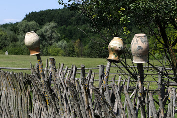 Old ceramic jugs on a wicker fence