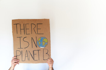 Hands holding a cardboard sign with there is no planet b slogan over wihte background