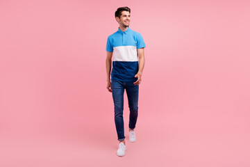 Fototapeta na wymiar Full size photo of optimistic brunet young guy go look empty space wear polo jeans sneakers isolated on pink background