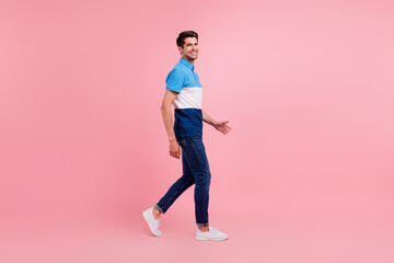 Full length profile photo of nice brunet young guy go wear polo jeans sneakers isolated on pink...