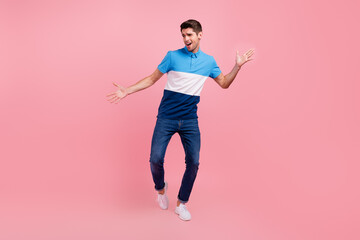 Full size photo of funky brunet young guy dance wear polo jeans sneakers isolated on pink background
