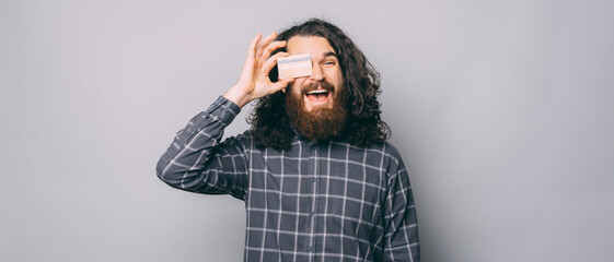 A photo of a man holding a credit card and looking at the camera is excited