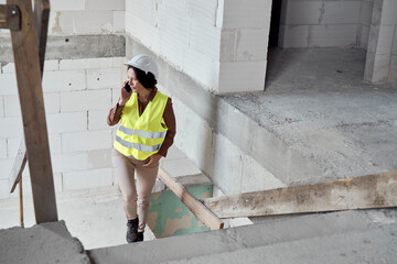 Waist up video of female caucasian engineer on the construction site talking on the phone and...