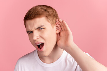 Photo of young man arm near ear listen amazed shocked fake gossip information isolated over pink color background