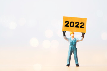 Worker man holding yellow paper with 2022 year for preparation happy new year and start new business plan.