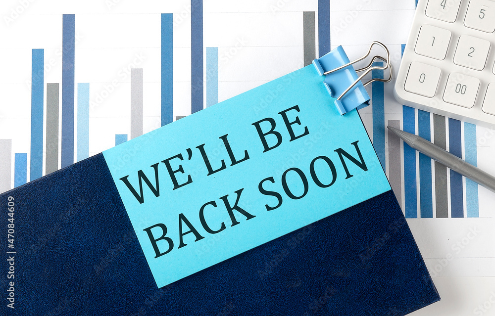 Poster we'll be back soon on sticky note on notebook on the chart background