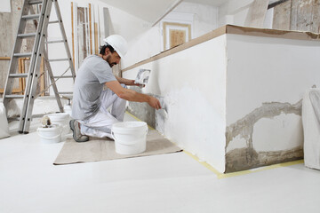 plasterer man at work, take the mortar from the bucket with trowel to plastering the wall of...