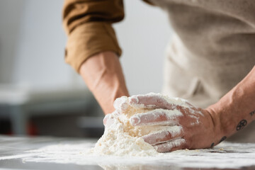 Cropped view of blurred chef making dough on kitchen table