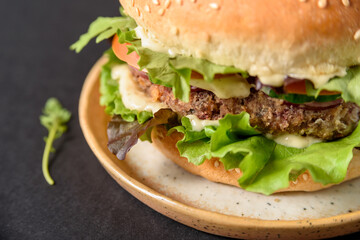 Vegetarian burger with bean patty and vegetables on black background close up