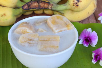 Banana in coconut milk. Fruit dessert. Top view with ripe bananas on white wooden table.