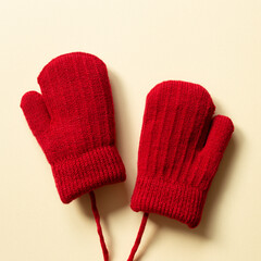 Winter red knitted gloves on beige background. top view, copy space