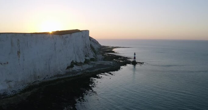 Drone shot of lighthouse by large cliffs