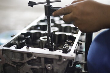 the hand of a mechanic is installing the valve seal of an overhauled car engine - obrazy, fototapety, plakaty