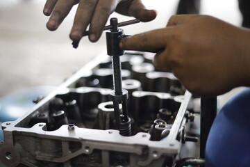 the hand of a mechanic is installing the valve seal of an overhauled car engine