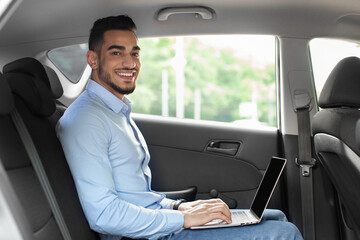 Handsome arabic entrepreneur sitting at auto, using laptop, mockup