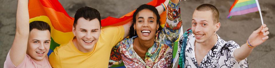 Multiracial friends with rainbow flag hugging during pride parade