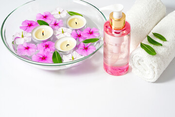 Obraz na płótnie Canvas Body care supplies, white towel, oil and rose flowers on a white background, Burning floating candles in a bowl of water, spa relaxation and meditation