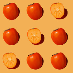 Autumn pattern is made with half a persimmon on a orange background.