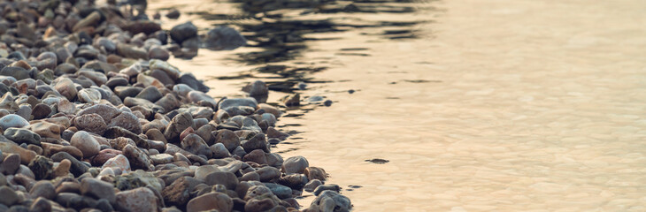 Beach pebbles and sea water in sunrise
