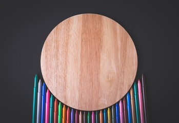A set of different color markers on a wood background.