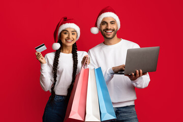 Holiday Shopping Online. Cheerful arab couple posing with laptop and credit card