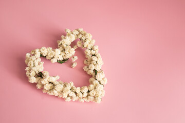 Heart shape from gypsophila flowers in pink background. Top view, copy space.
