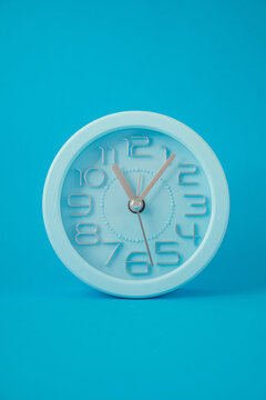 table clock in the middle of the image, isolated on a light blue background