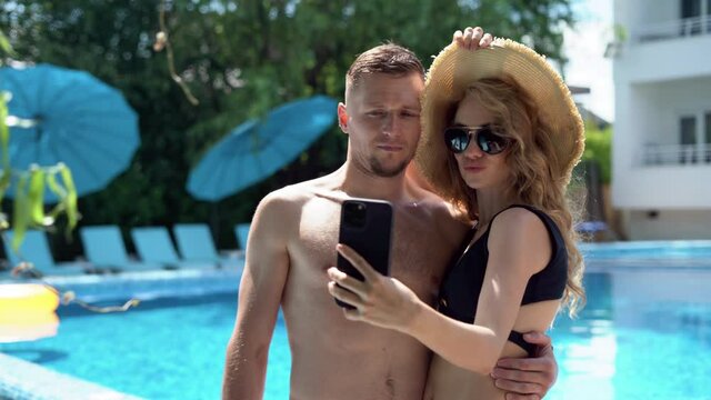 romantic date of a sexy couple near the swimming pool make selfie with the phone camera. Relaxation for lovers in a modern spa hotel. Photo by smartphone family on vacation. Trip concept