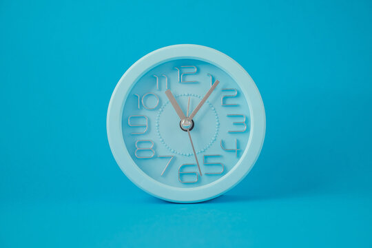 table clock in the middle of the image isolated on blue background