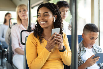 Happy black woman listening music in bus © Prostock-studio