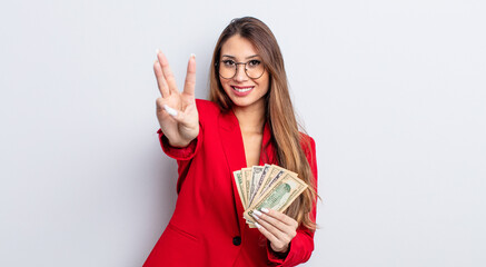 asiatic pretty woman smiling and looking friendly, showing number three. business and banknotes...