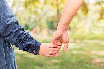Child holding father's hand walking in the park