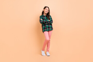 Fototapeta na wymiar Photo of funky cool schoolgirl wear plaid outfit dancing arms crossed smiling isolated beige color background