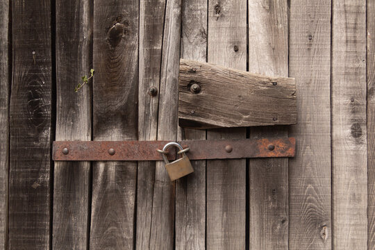 Old wooden door background with metal. Abstract old wood texture.Closed door, padlock, threshold, rust and roots.